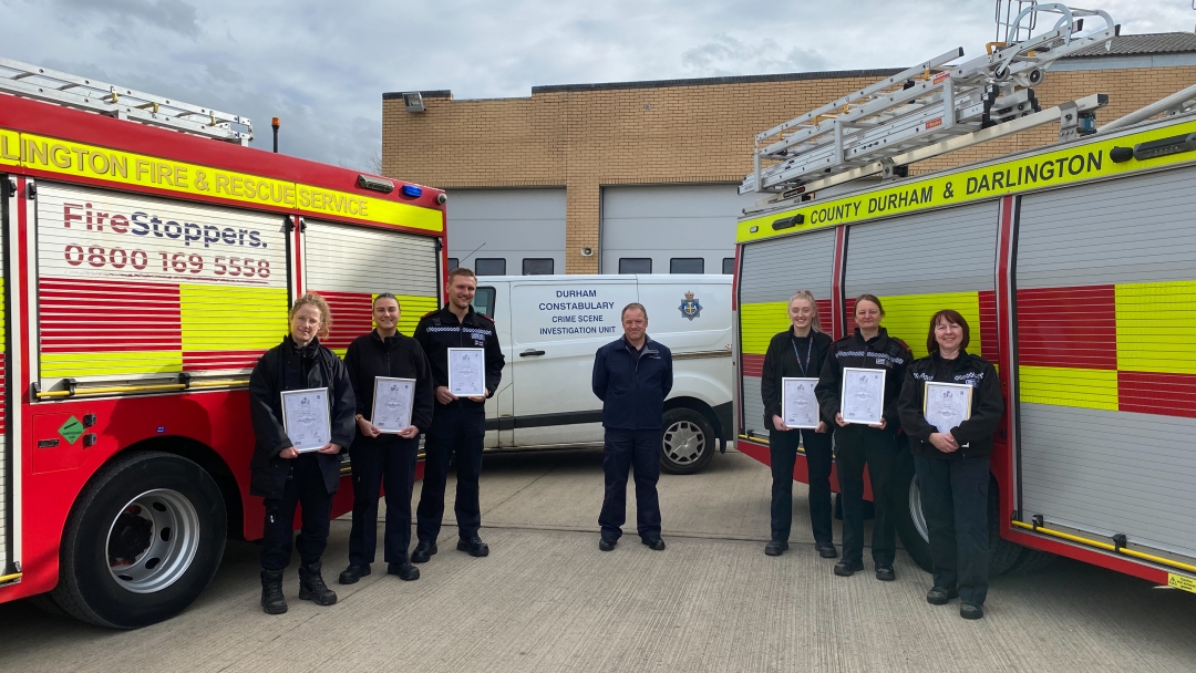 6 CSI's holding accreditation in front of two fire appliances 