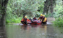 firefighters in a boat on a flooded street