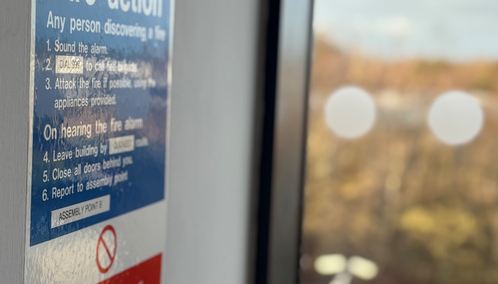 A picture of a poster hanging in a building with fire action instructions