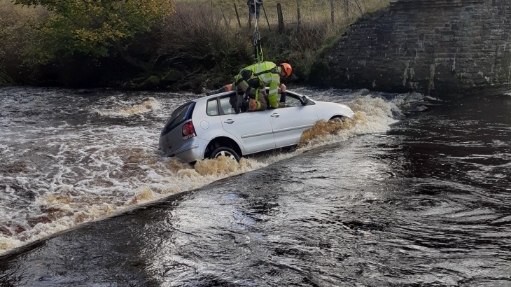 Firefighter rescuing occupant from car in ford