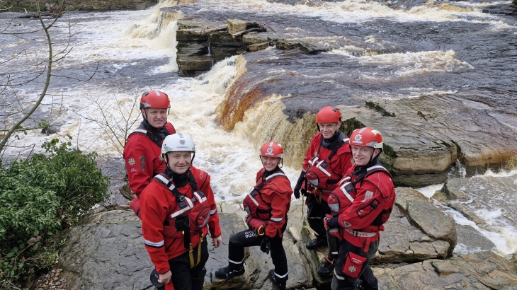 Bishop Auckland firefighters wearing water rescue gear and standing by a river.
