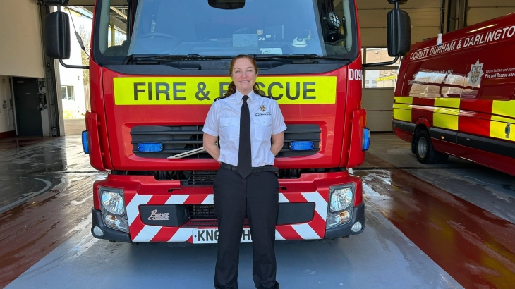 Lindsay Blake wearing white shirt and black trousers standing in front of a fire engine. 