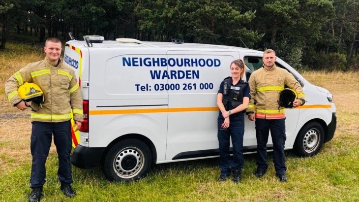 Two firefighters wearing fire kit and standing in front of a neighbourhood warden van with a neighbourhood warden in Chester-le-Street. 