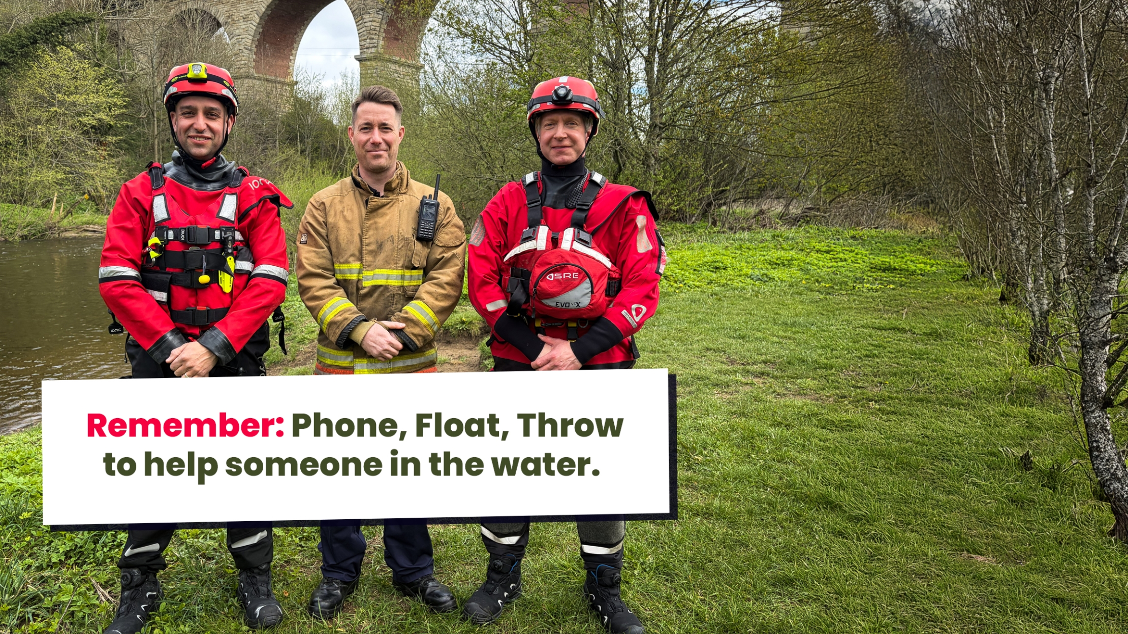 Three firefighters wearing water safety gear standing by a river. 