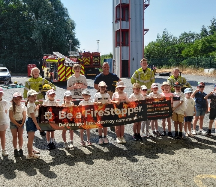 be a firestopper banner held by young students in front of firefighters and an appliance