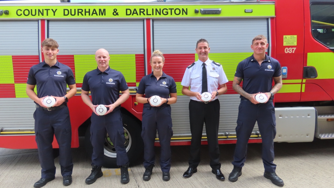 Firefighters with smoke alarms outside a fire engine