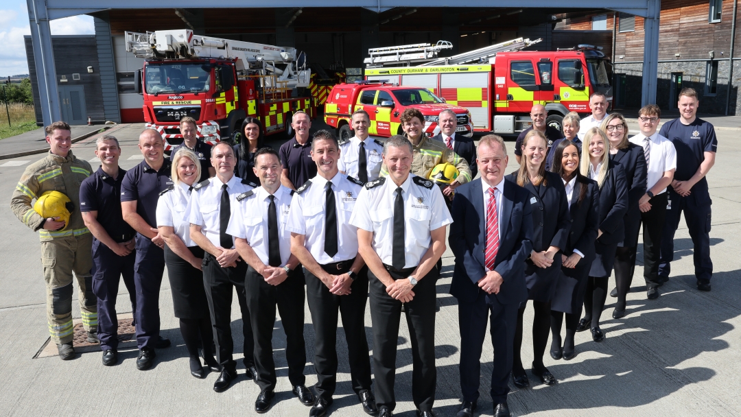 Chief Fire Officer Steve Helps and Service staff outside of Durham fire station with fire engines in background. 