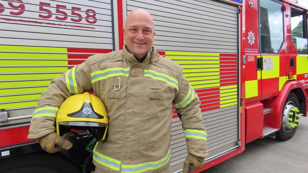 On-call firefighter Karl Sichert standing in front of a fire engine. 