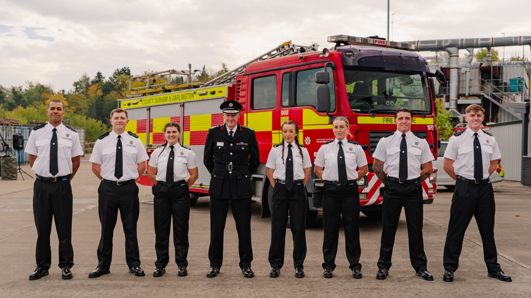 Seven firefighters from Cohort 8 pictured wearing white shirts in front of a fire engine with Chief Fire Officer in black uniform in centre. 
