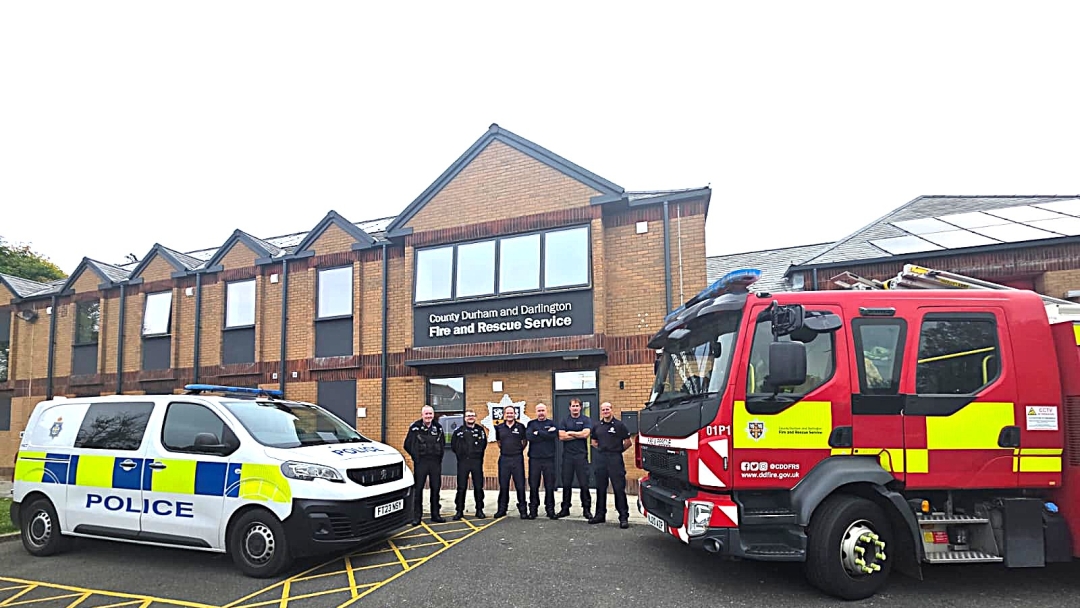 Firefighters and PCSO's standing in a line outside of Consett Fire Station with police car and fire engine in the background. 
