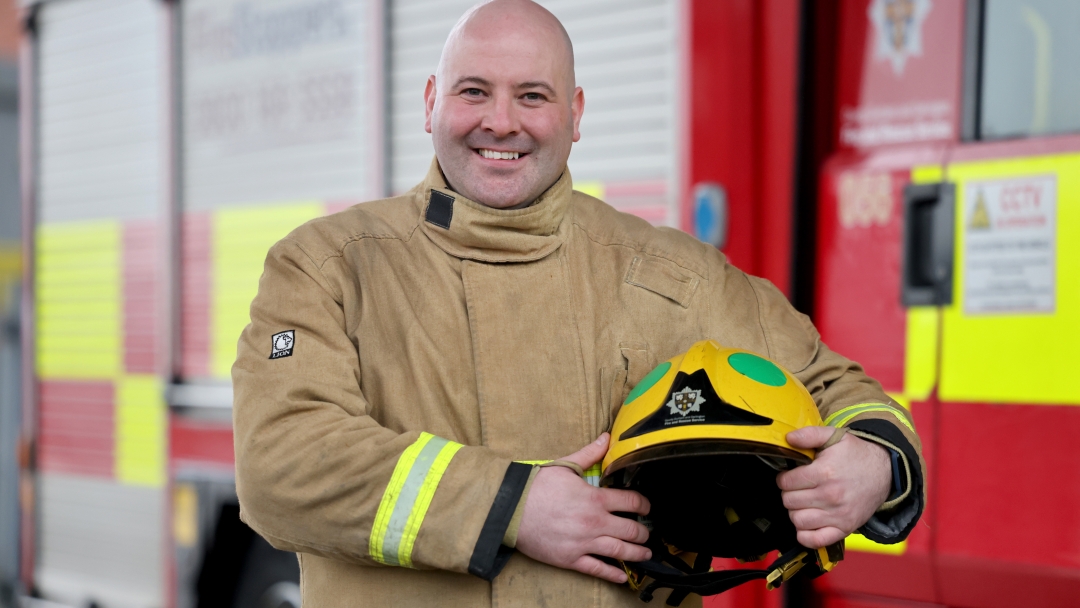 Crook on-call firefighter Stuart Proud wearing fire kit and holding his helmet. 