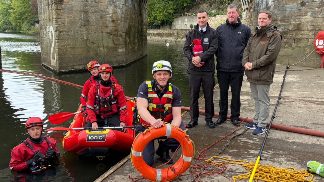 Durham firefighters wearing water rescue kit on riverside. 